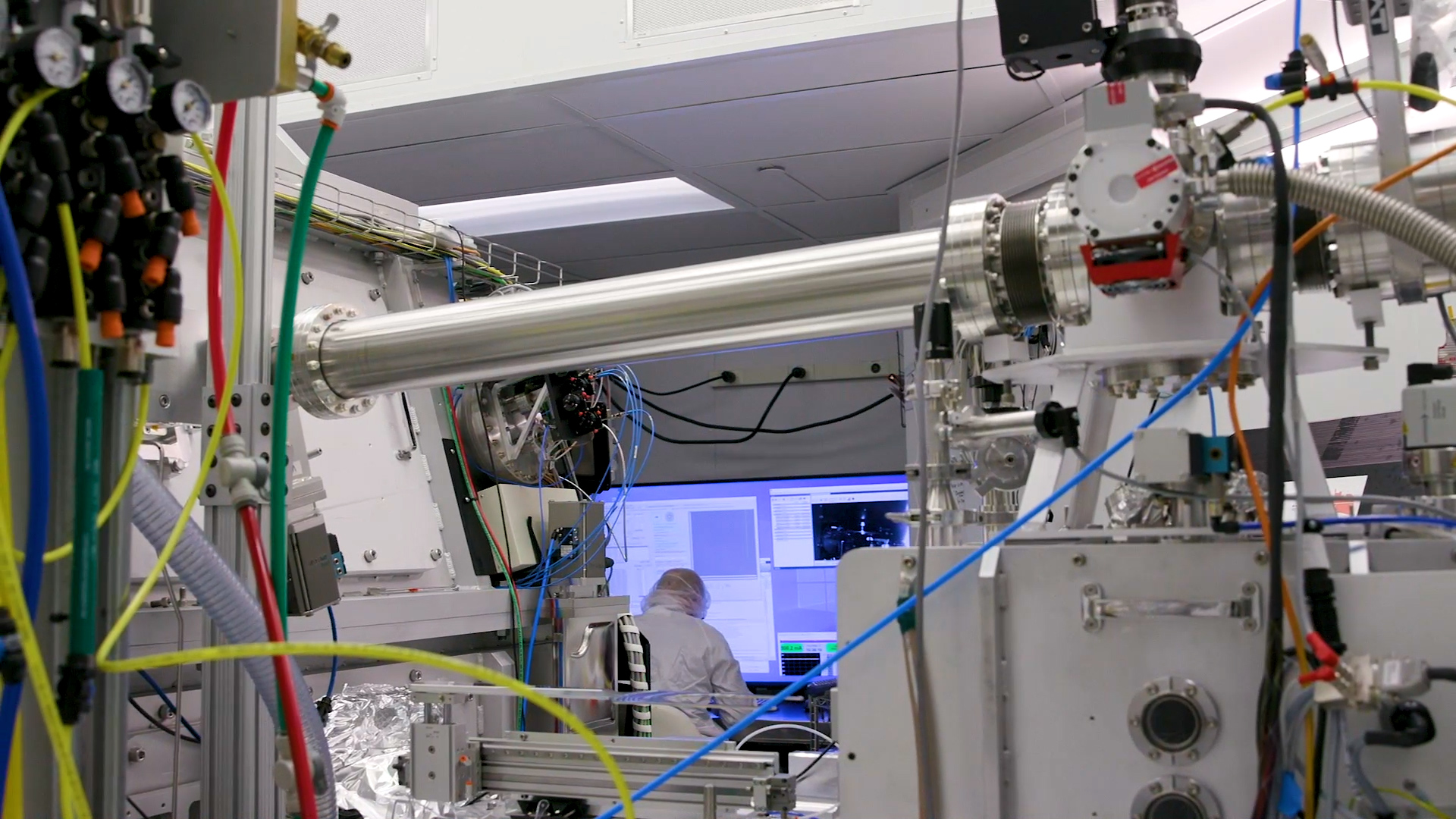 A scientist works at the computer with machinery in the foreground at the Center for X-Ray Optics.