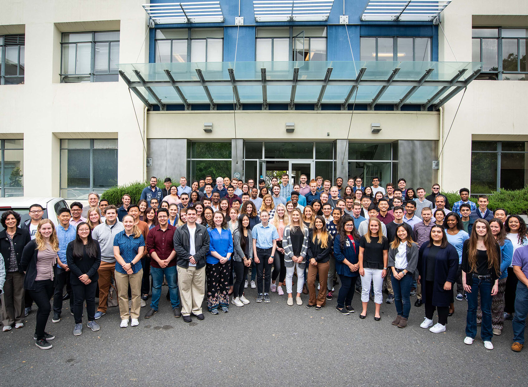 Group of 50 to 80 individuals standing in front of a building.