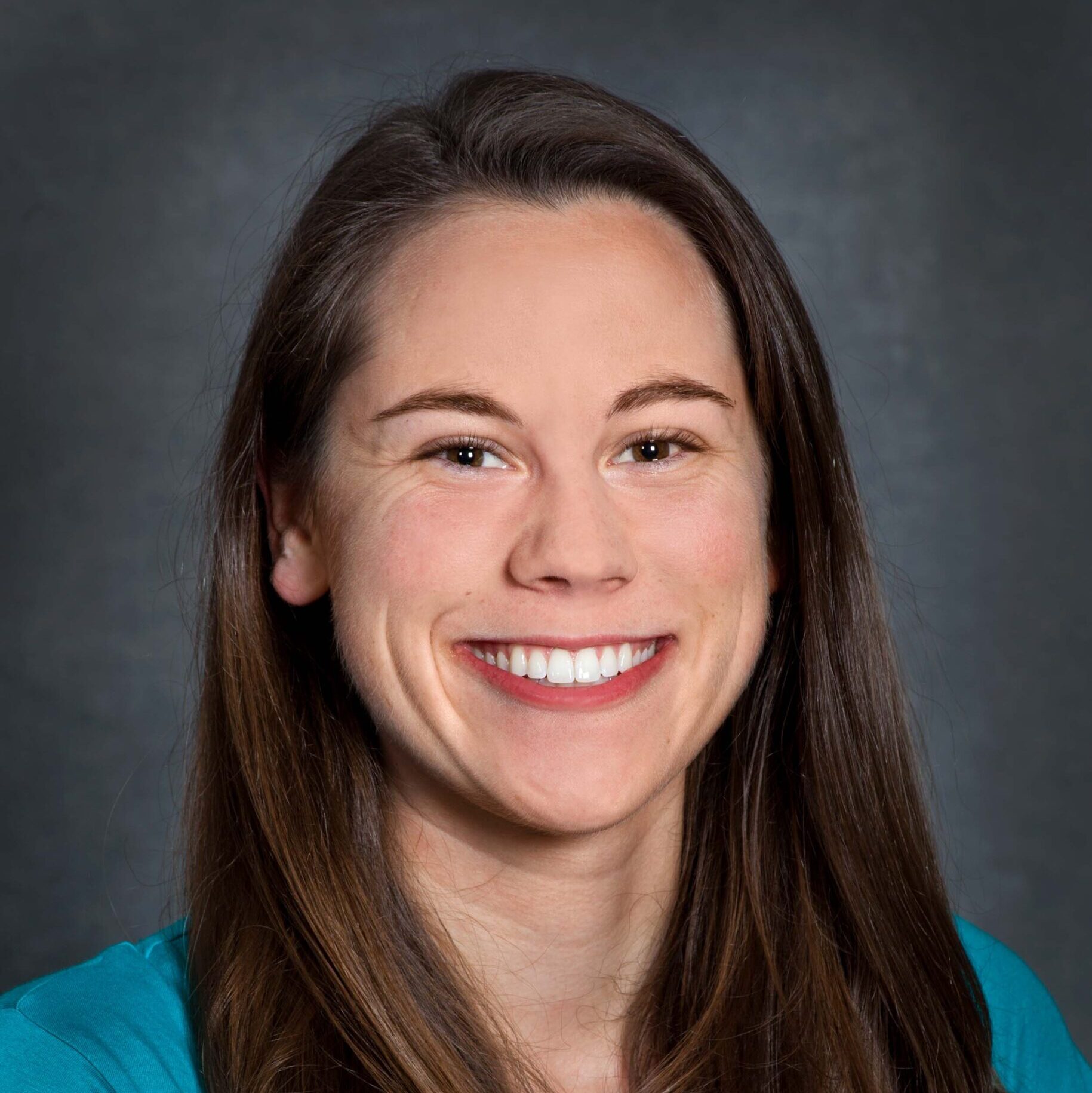 Dark-haired person with brown eyes wearing a teal shirt.