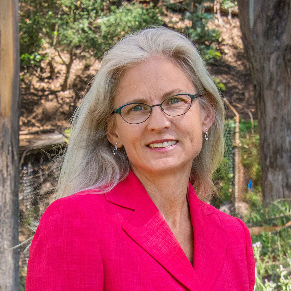 Light-haired person in glasses wearing a bright pink blazer.