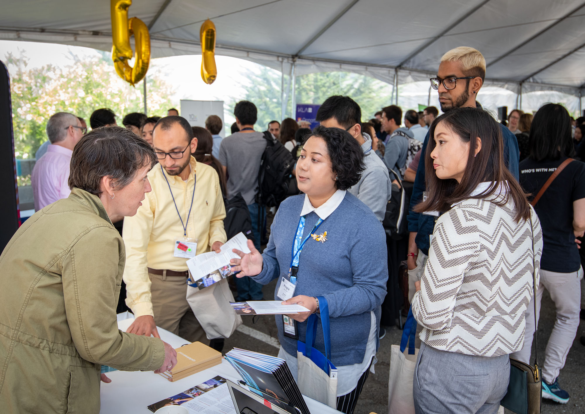 A group of postdocs converse with a presenter at an outdoor postdoc networking event.