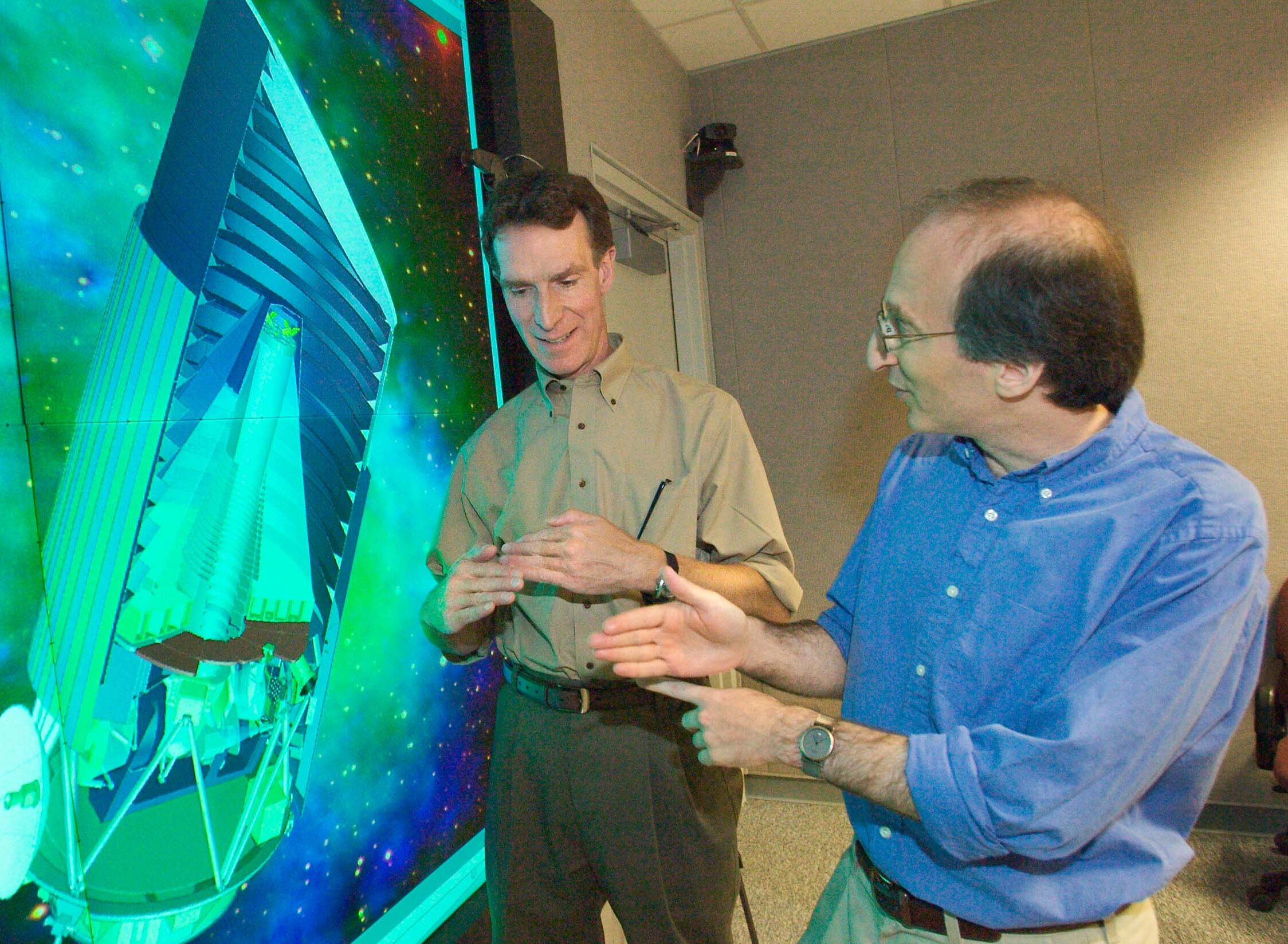 Saul Perlmutter with Bill Nye in front of a multiscreen.