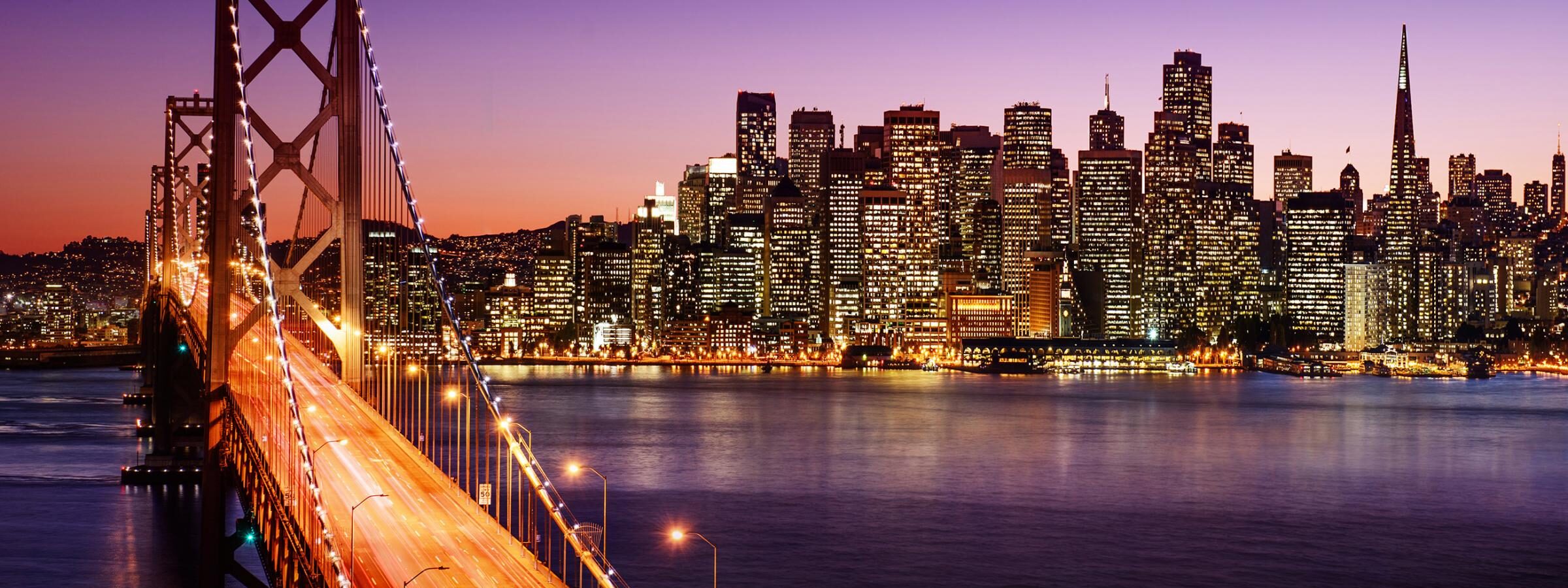 Evening view of the San Francisco Bay Bridge, with downtown San Francisco in the background..