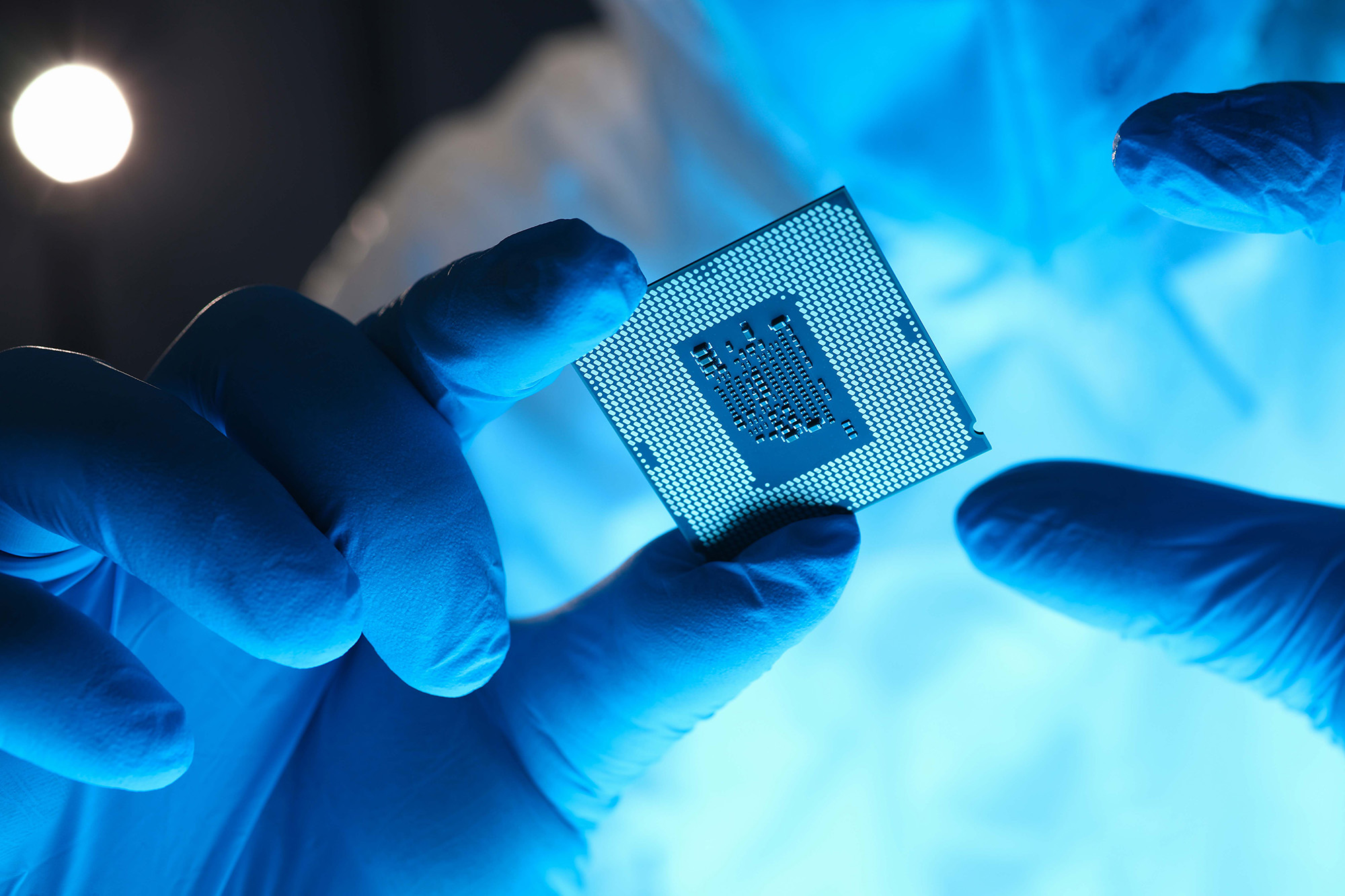 Gloved hands holding a square microchip.