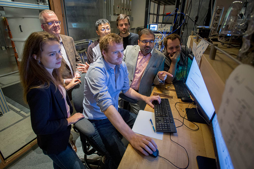 Seven researchers surrounding a computer monitor.