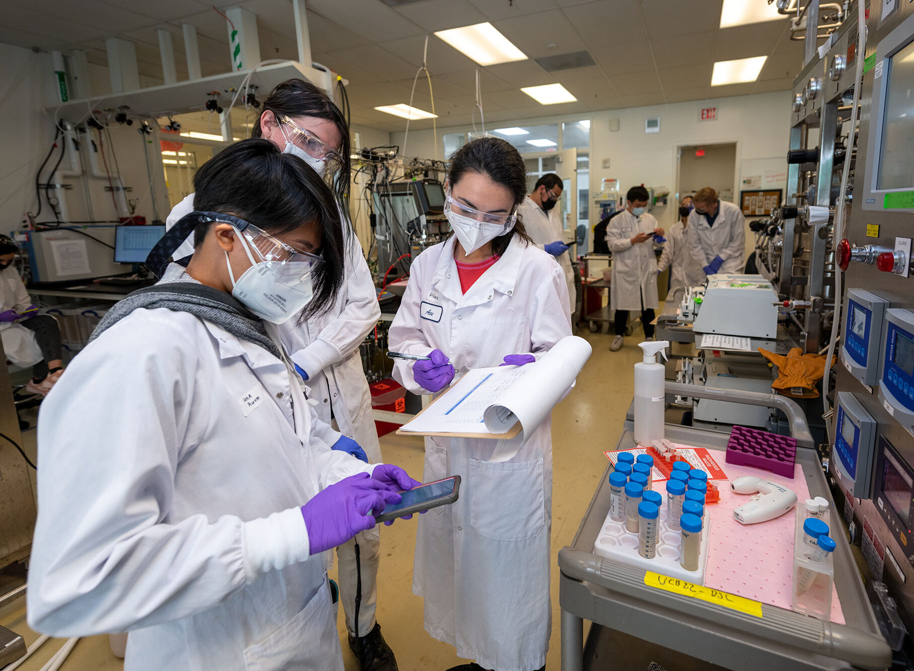 Large group of student scientists hold scientific instruments in a laboratory.