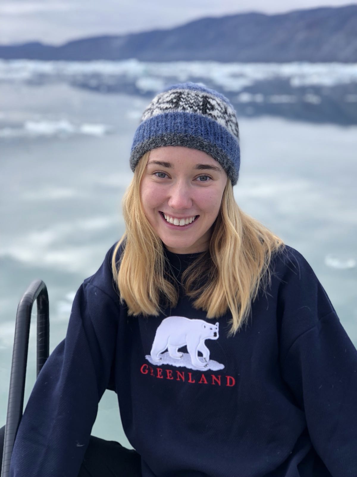 Helen Weierbach, a light-haired person wearing a beanie and a dark sweater smiles outdoors.