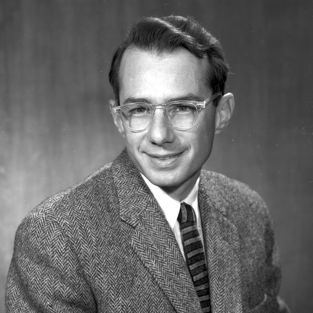 Black and white portrait of Arthur Rosenfeld, a short-haired person wearing a suit and tie.