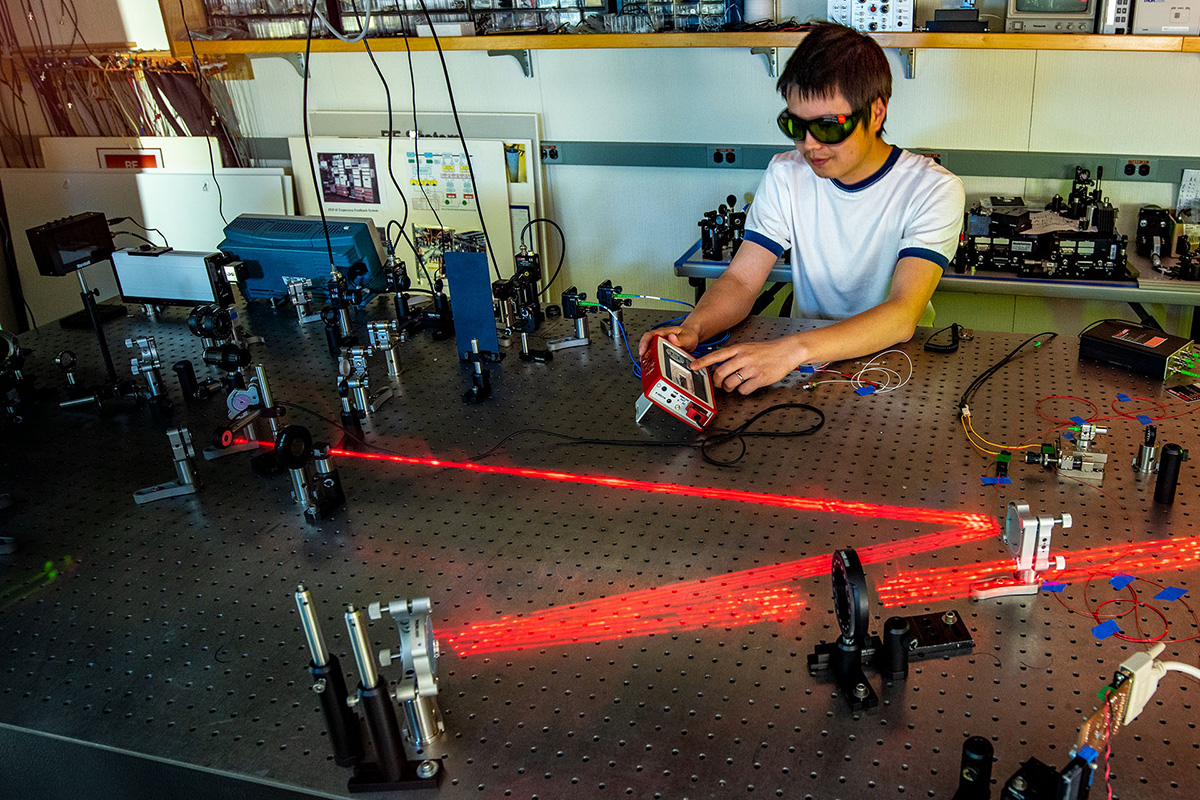 Scientist working with red lasers on a benchtop.