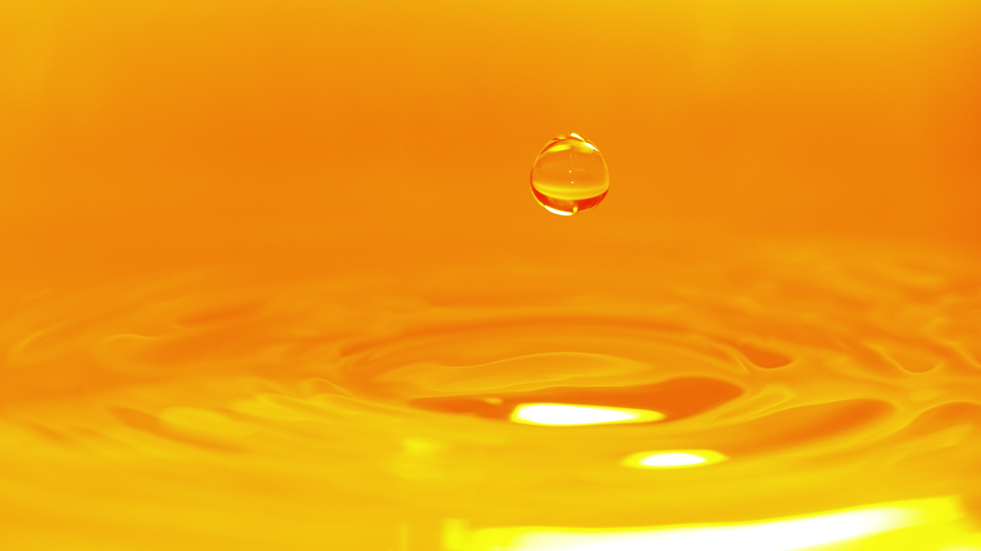 Orange droplet of water and rippling pool.