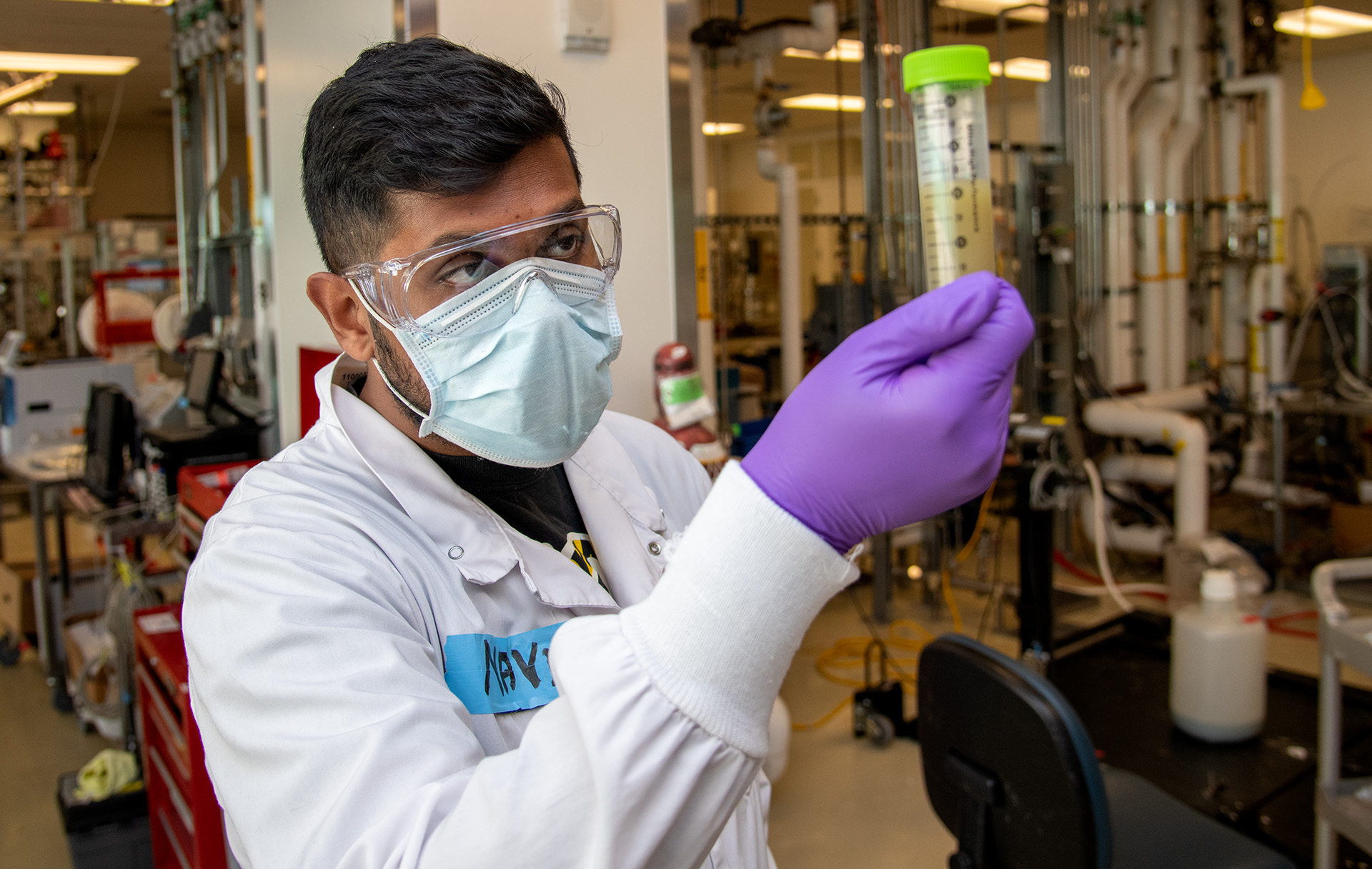 Masked scientist holding a vial.