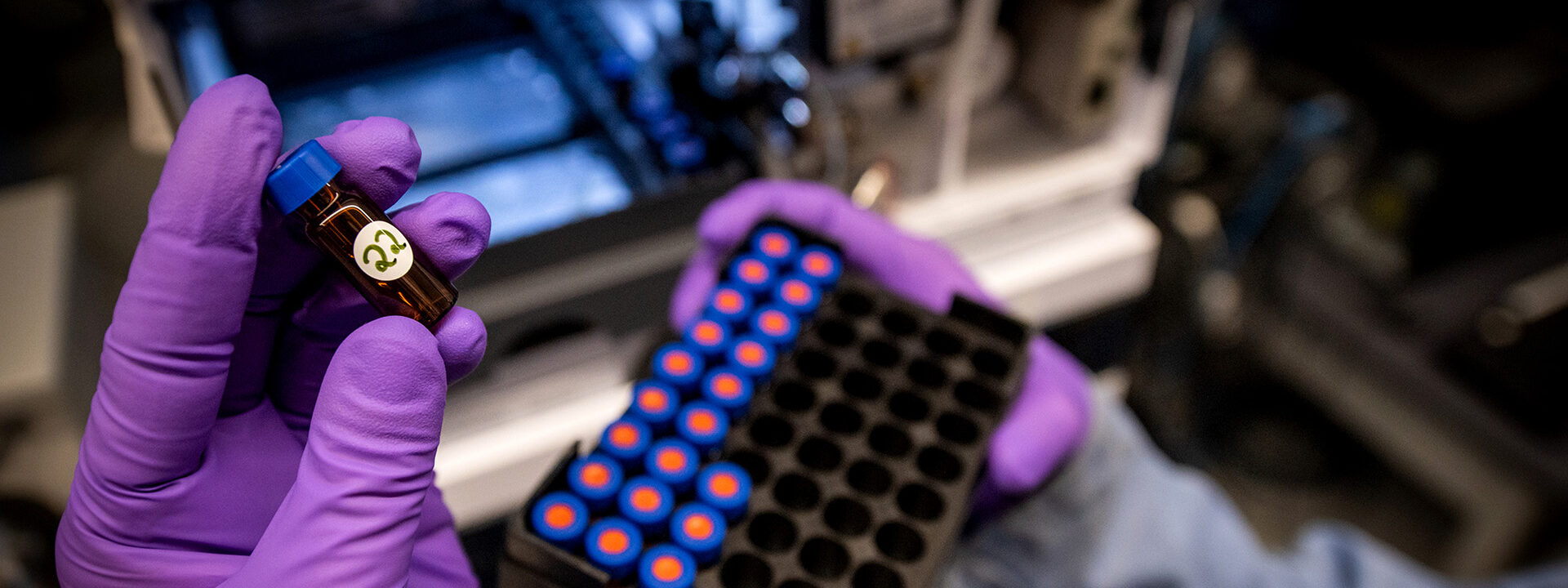 Gloved hand holding a sample vial.