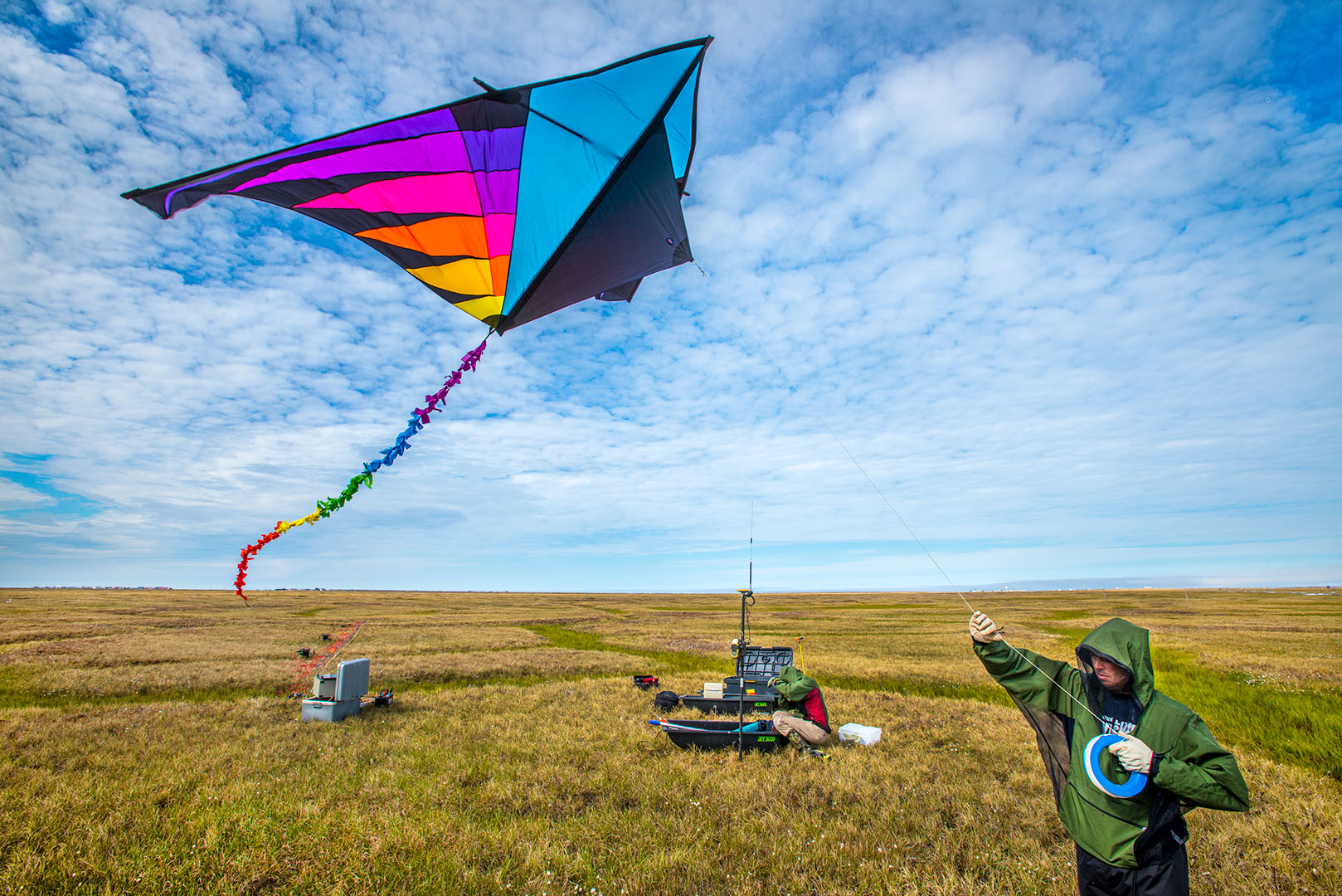 A colorful kite flying over a scientific field site.