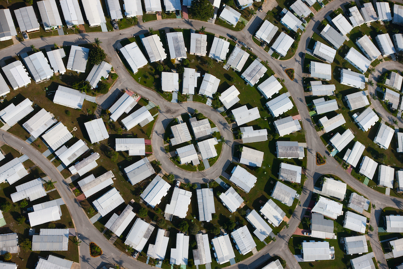 Aerial view of white roofed homes and streets forming circular patterns.