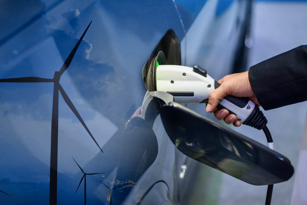 A hand plugs in a charging cable in an electric car.