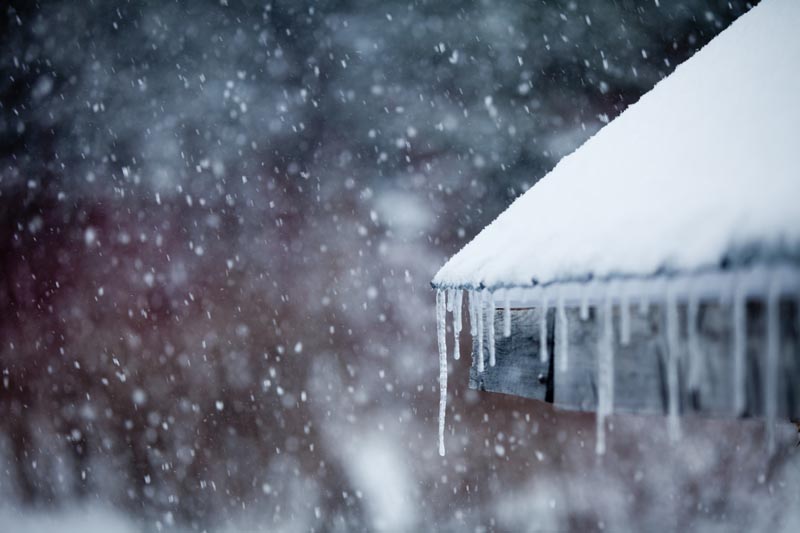 Closeup of snowy roof with icicles.