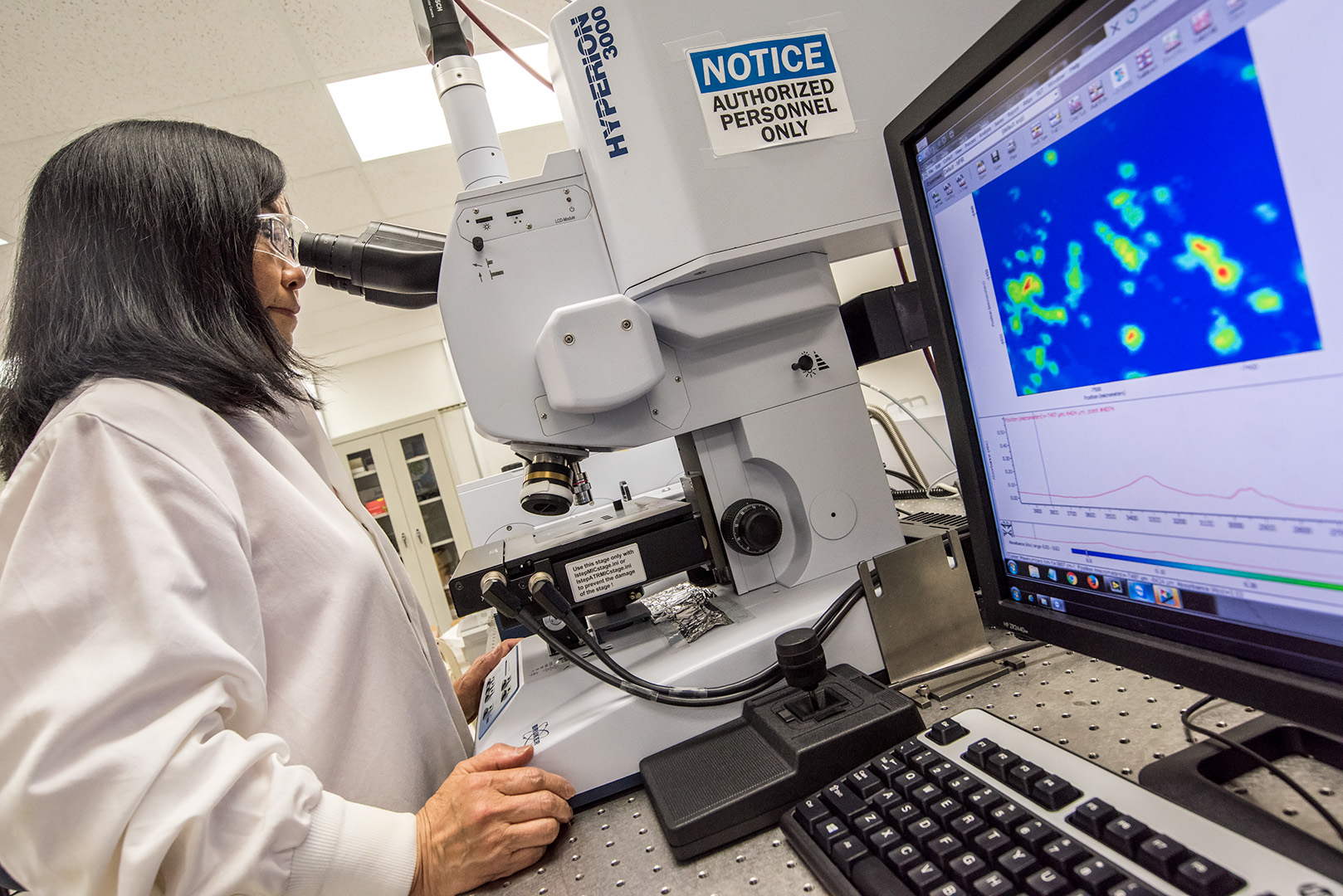 Scientist in a lab coat looking into a microscope.