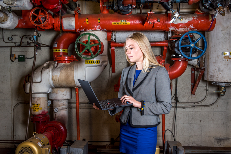 Person holding a laptop in a boiler room.