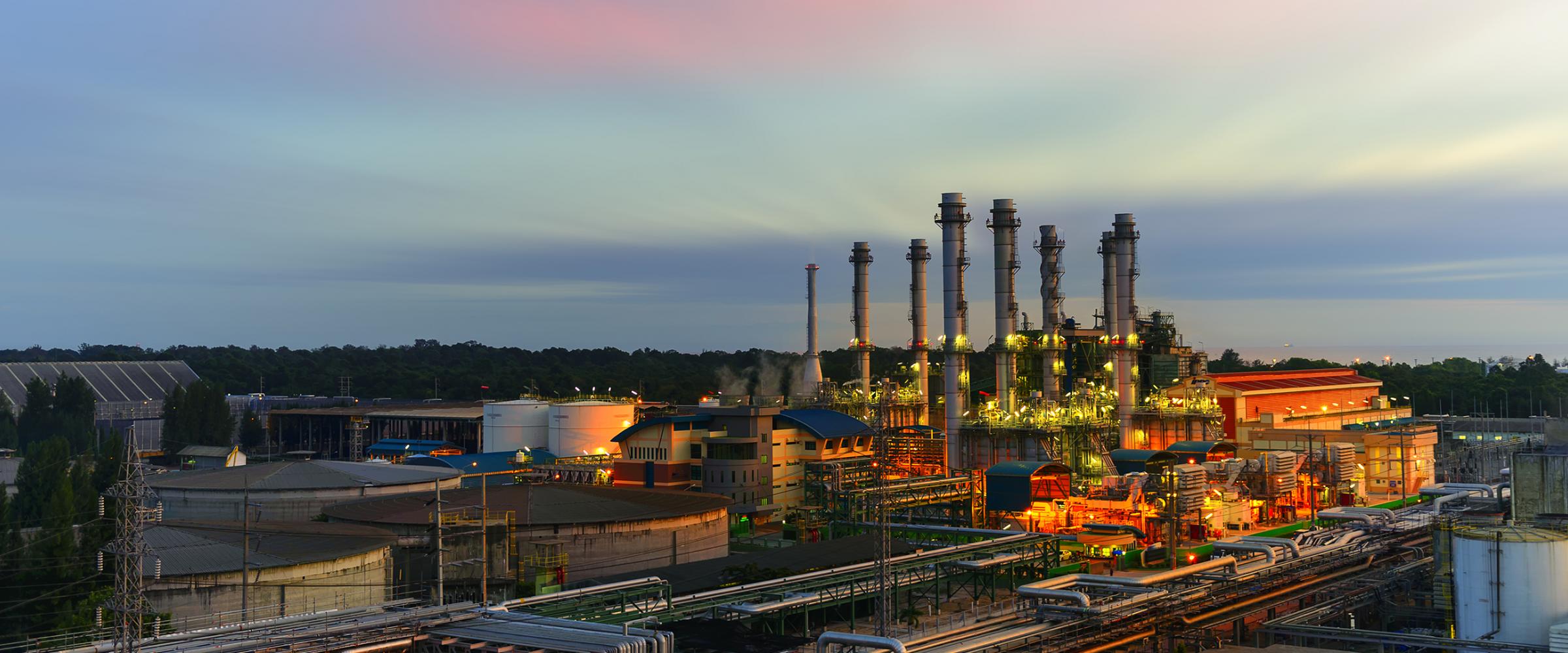 Exterior view of a glowing energy industrial factory at sunset.