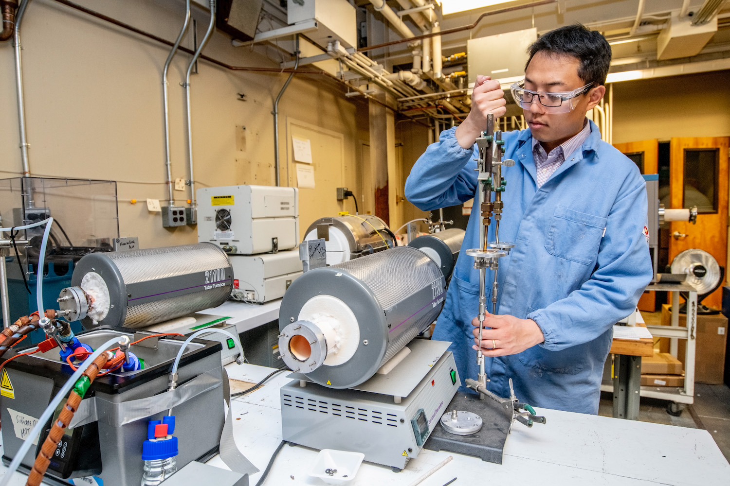 Scientists holding a piece of machinery at a lab bench.