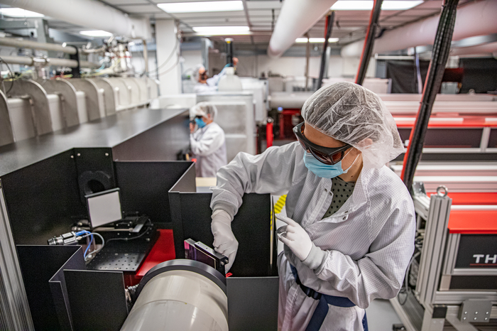 Scientist in a hair cap and goggles work on accelerator technology.