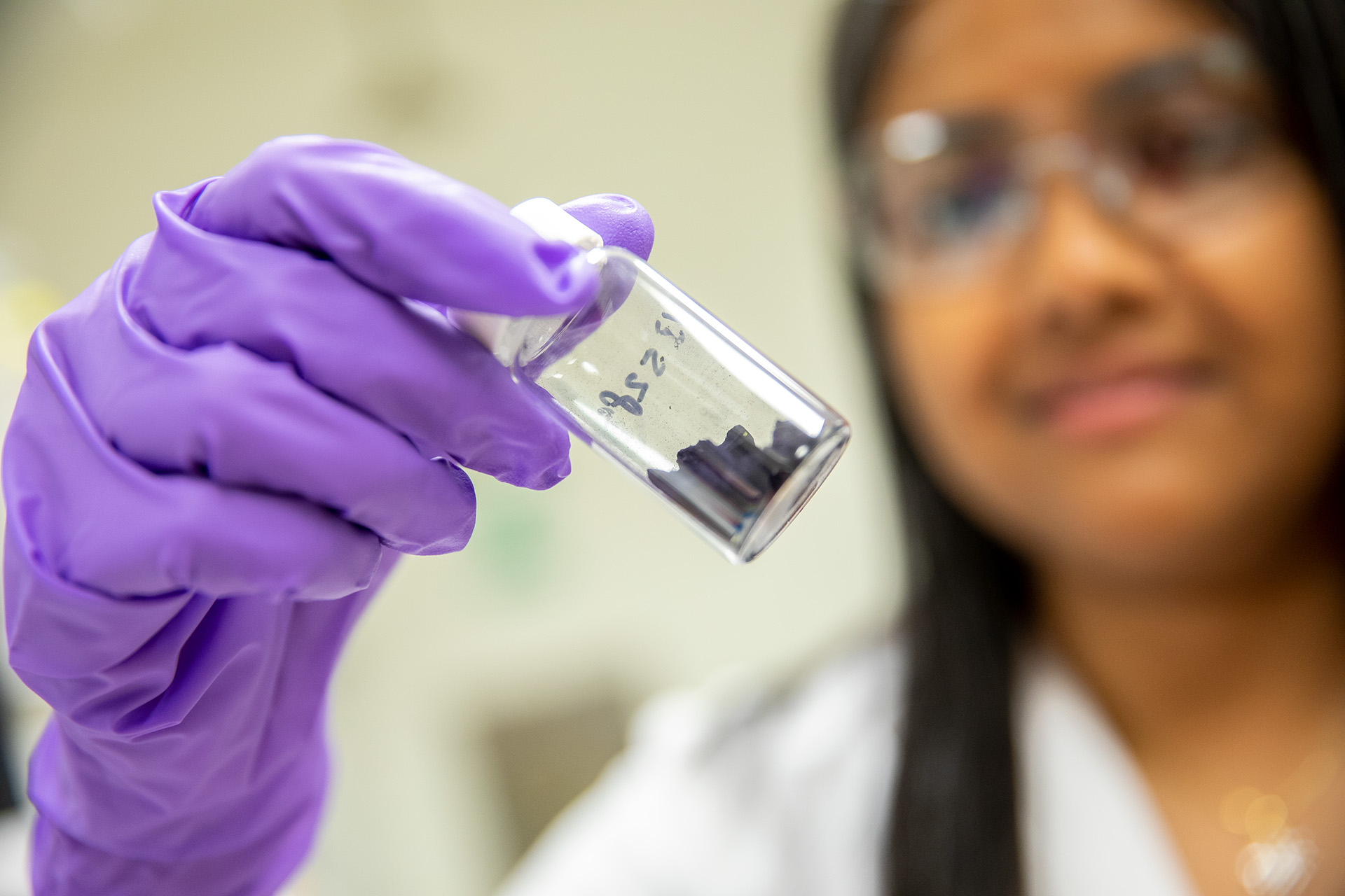 Scientist holding a sample in a small sample jar.