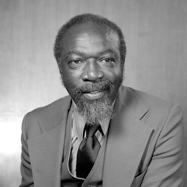 Black and white portrait of James (Jim) Harris wearing a suit for his headshot.