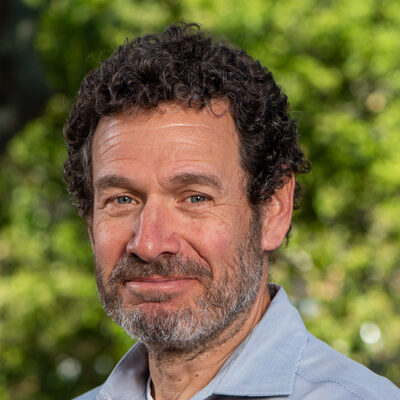 Dark-haired person with beard wearing a blue shirt.