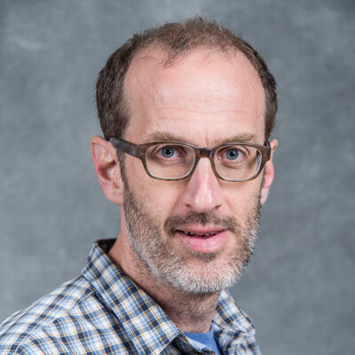 Smiling person in a blue, gingham patterned shirt