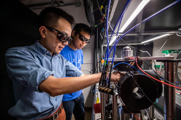 Two short-haired scientists in blue shirts prepare a laser