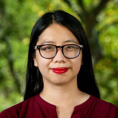 Dark-haired person in glasses wearing a maroon colored shirt.