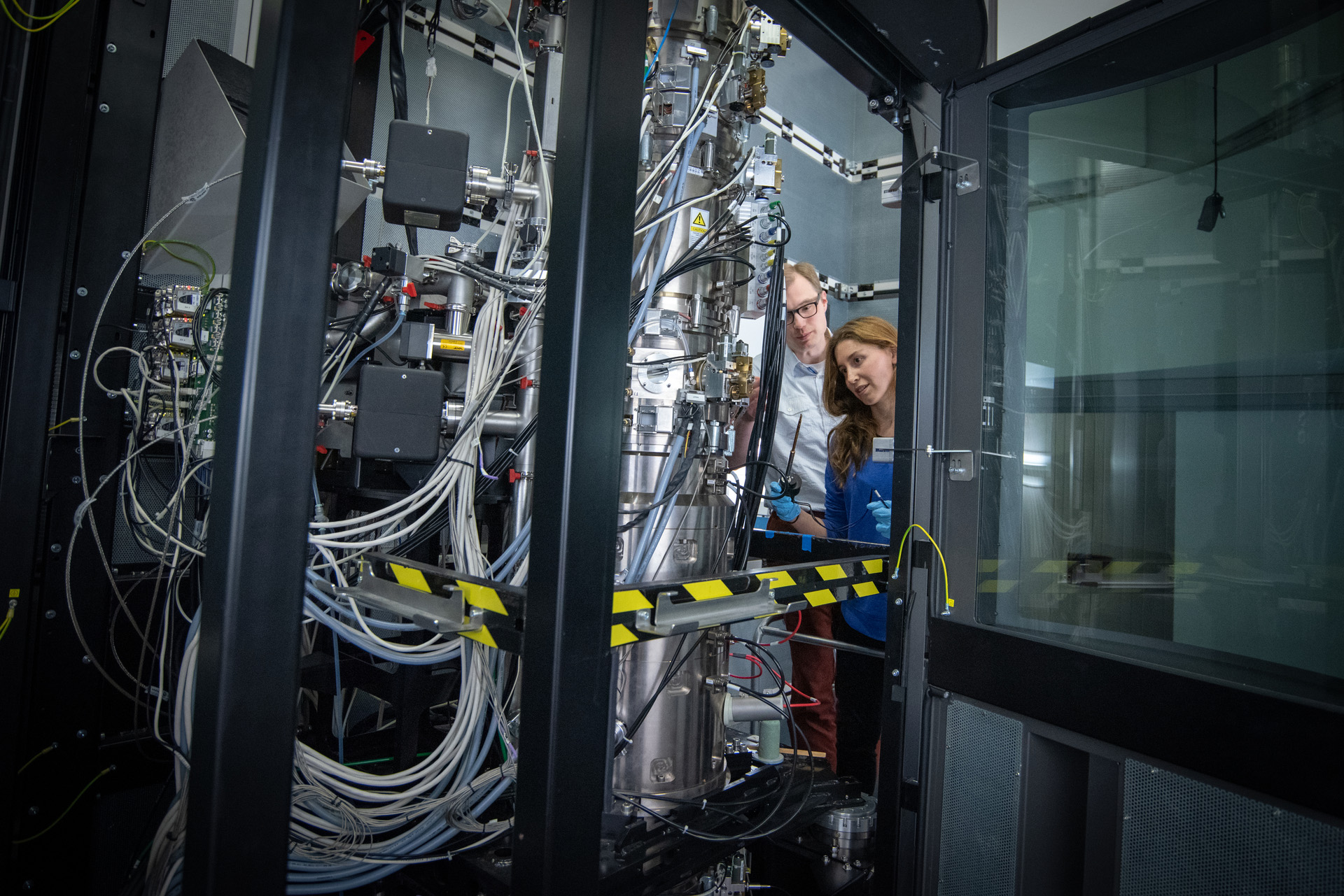 Two people looking into a large microscope facility.