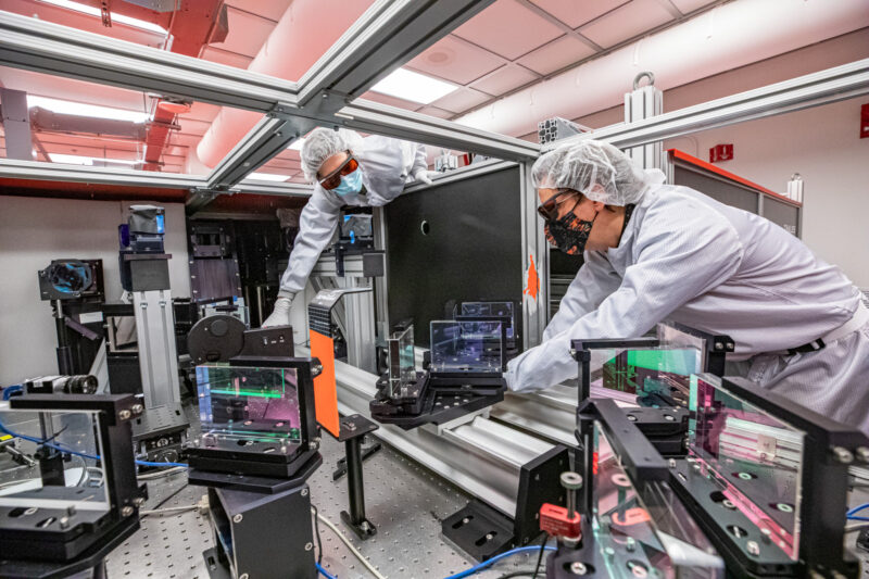 Two scientists perform work on the laser table where the petawatt laser is split into two beamlines.