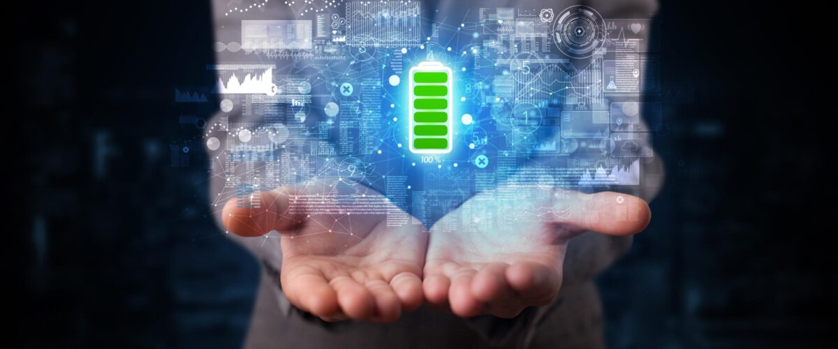 Digitally generated image of various scientific graphs and charts hovering over a pair of outstretched hands. A full battery icon is centered in the image.