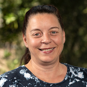 Person with dark hair wearing a dark blue and white patterned shirt.