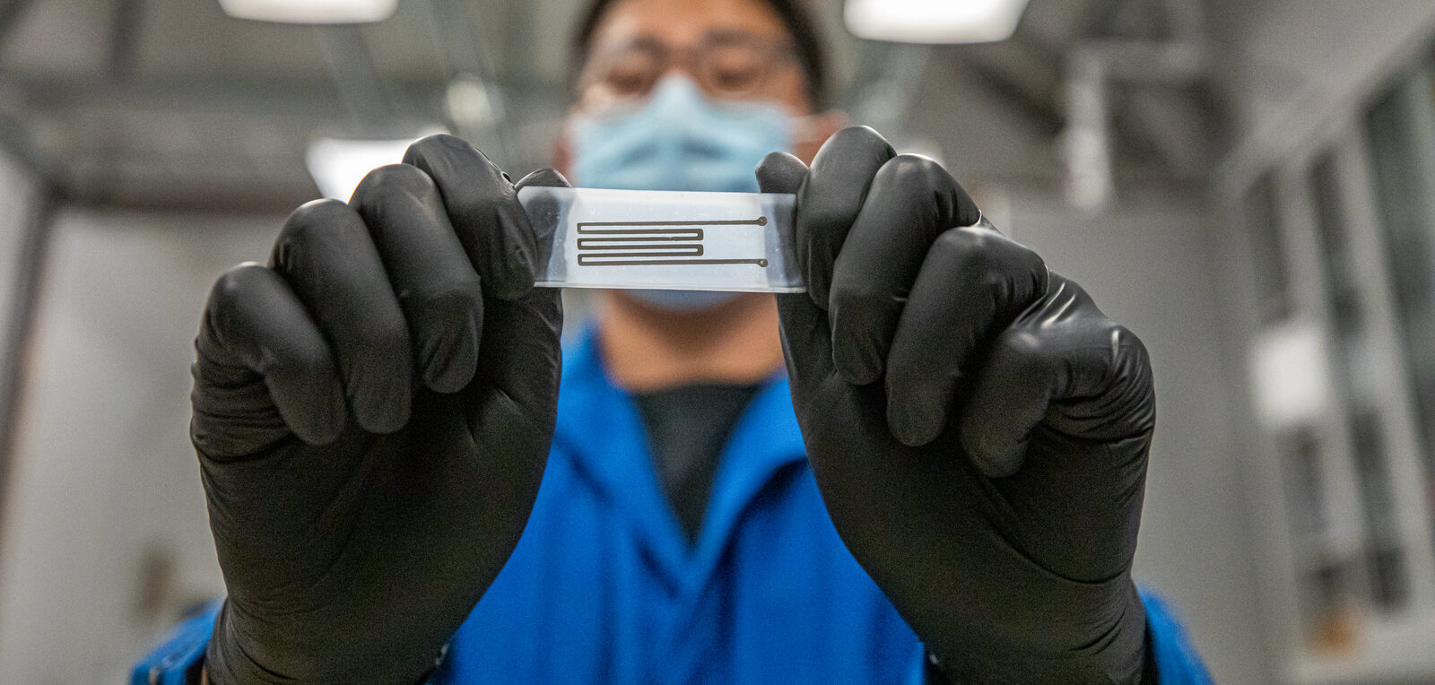 Scientist holds up a biodegradable printed circuit.