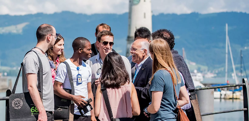 A group of people amicably talking with each other near the sea.