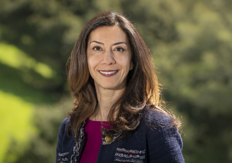 Person with medium-length brown hair wearing a dark blue cardigan over a maroon shirt.