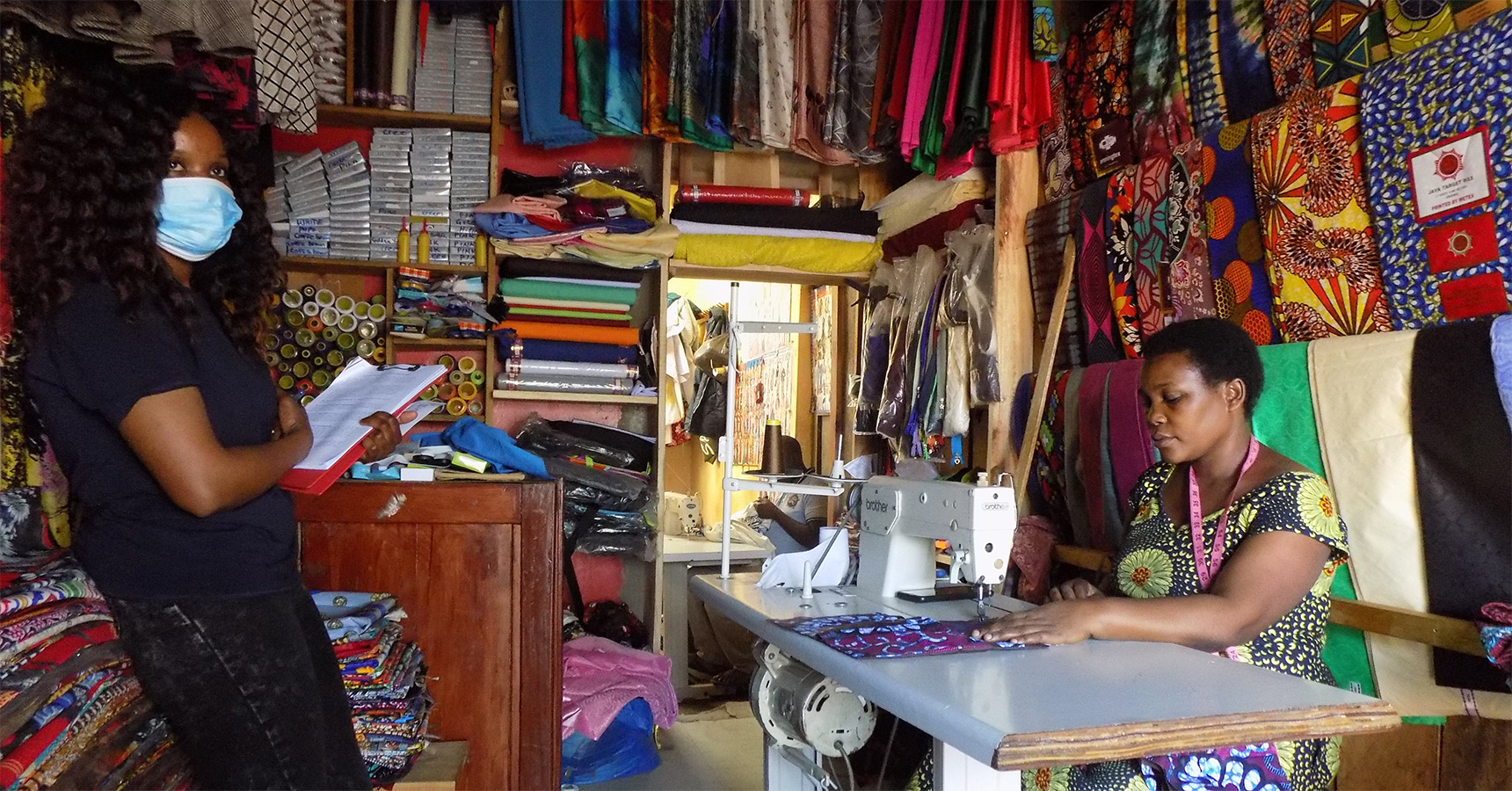 Two women standing at opposite sides of a colorful sewing room.