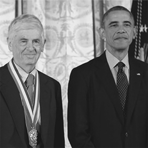 Two people standing next to each other in suits.