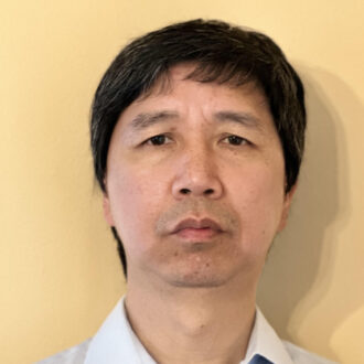 Tianzhen Hong, a person with short black hair wearing a light collared shirt, photographed against a yellow background.