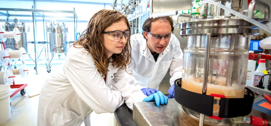 Two individuals leaning over an experimental lab setup.