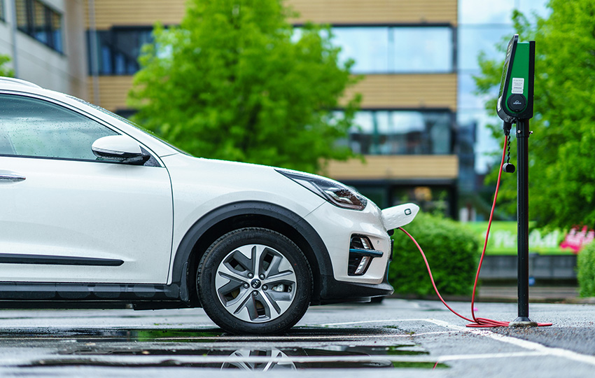 A white car parked at an electric vehicle charging station.
