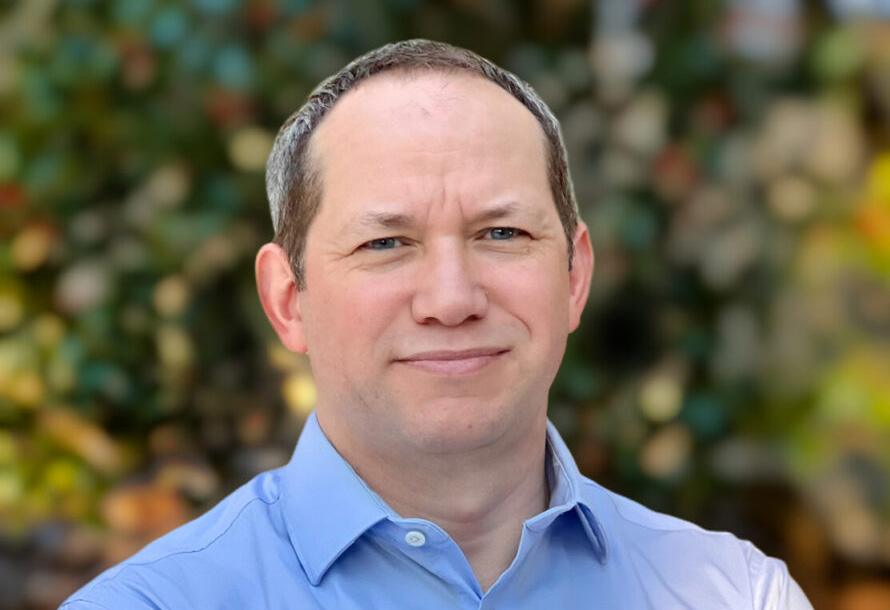 Alistair Rogers, a person with short brown hair wearing a light blue collared shirt.