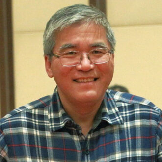 Smiling person in glasses and blue checkered flannel shirt.