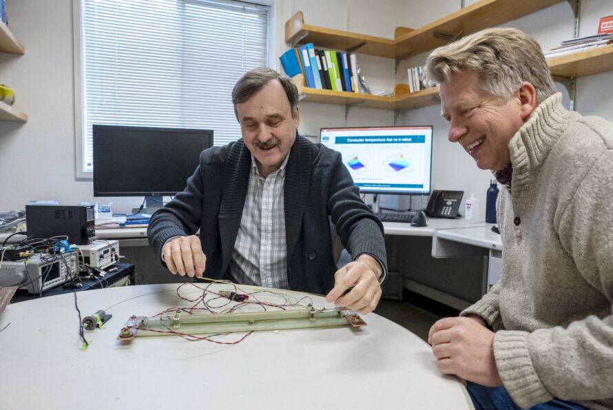 Maxim Marchevsky (left) and Soren Prestemon sit at a table to discuss an experimental setup to test the sensitivity of a temperature monitoring system for a high temperature superconducting magnet.