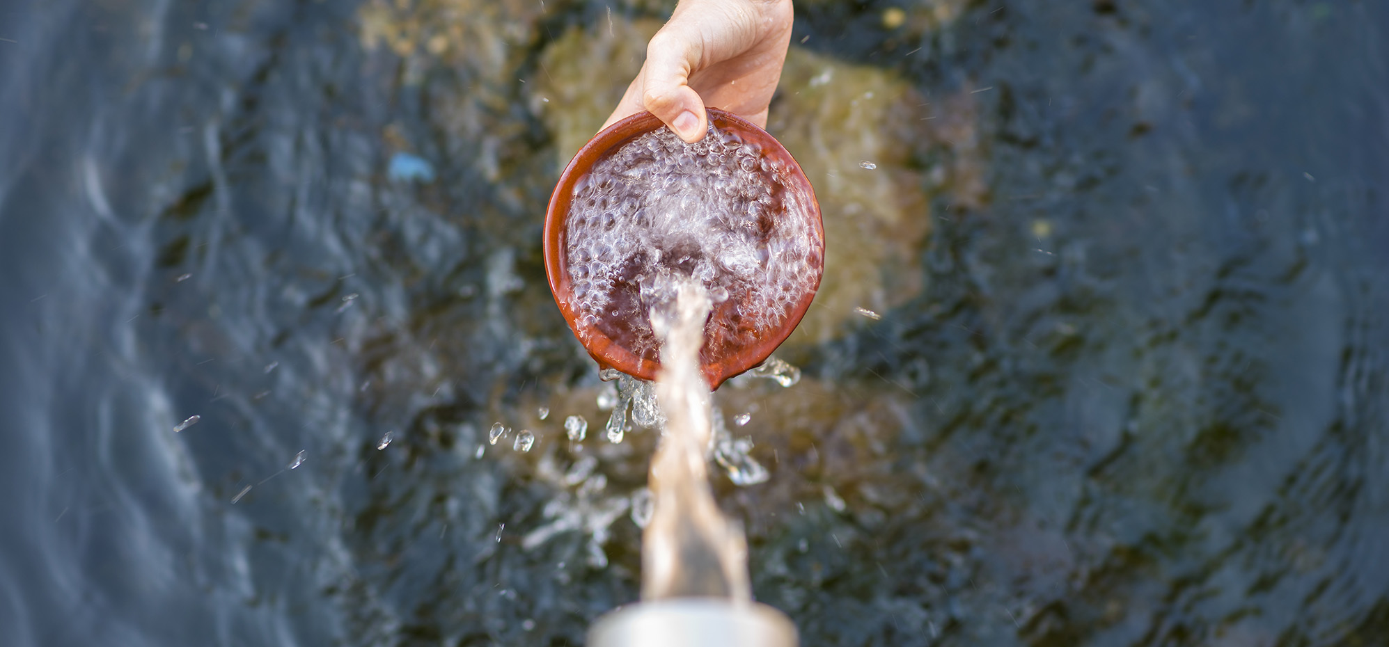 Outstretched hand holding a bowl collecting natrual water.