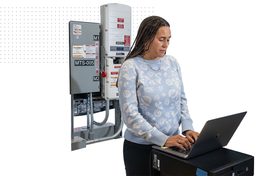 A person at a laptop desk in front of a grid power supply.