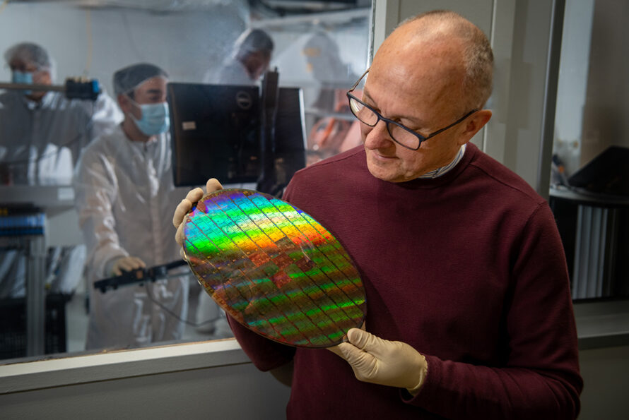 Person in a burgundy sweater holds a pancake sized disk of microchips.