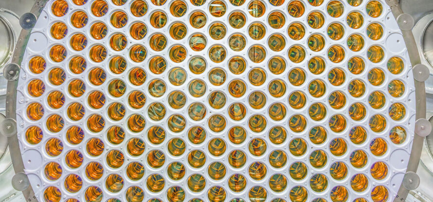 A circular array of amber, glossy photomultiplier tubes arranged in a grid pattern.